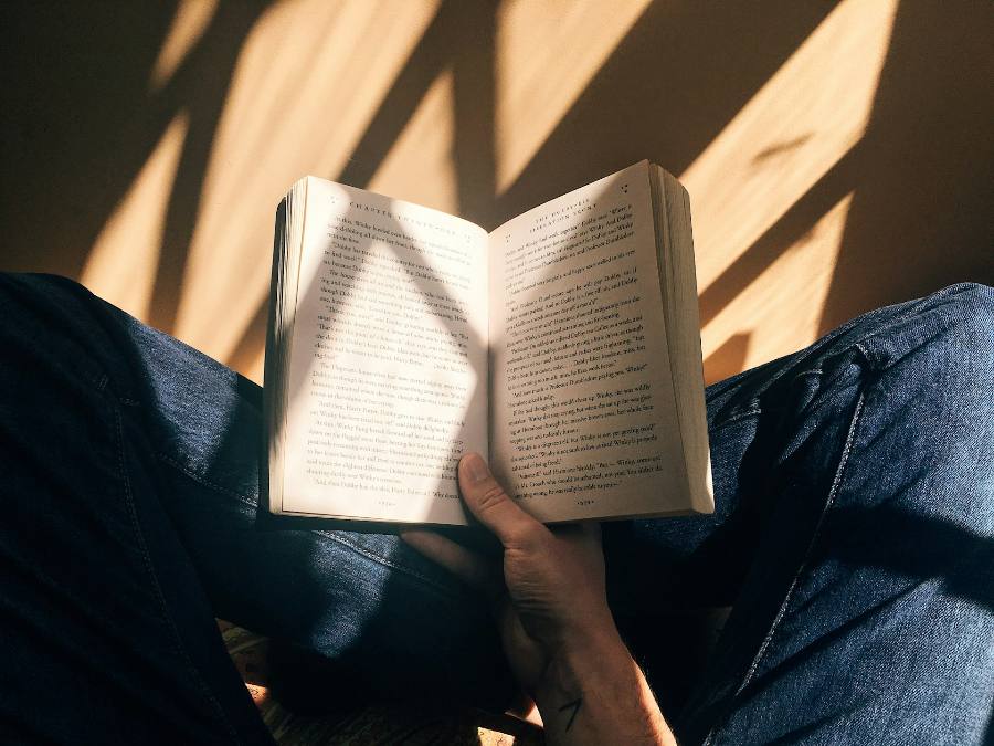 Una persona lee un libro abierto bajo una luz cálida